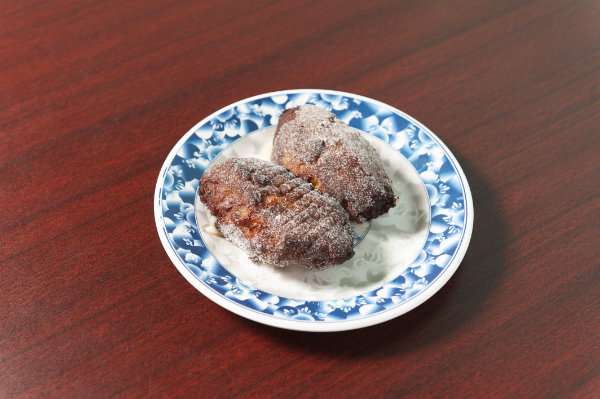 Two sugared empanadas de plátano on a blue and white plate.