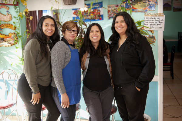 Marta and three of her daughters posing in the restaurant, smiling.