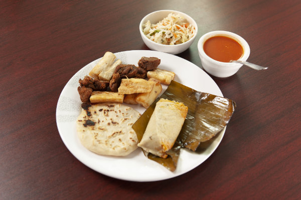 Combination plate with pupusa, yuca frita, chicharrón, and tamal.