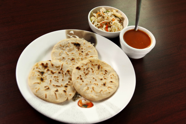 Plate of 3 pupusas served with sauce and a side.